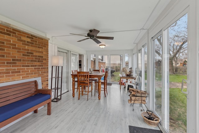 sunroom / solarium with brick wall, ceiling fan, and wood finished floors