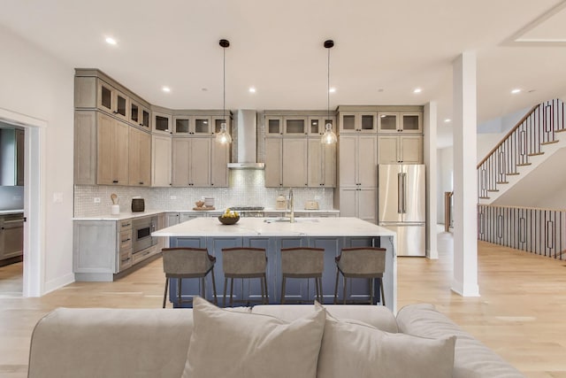 7302 Ponto Ct, Morton Grove, IL 60053 - kitchen with high end fridge, wall chimney range hood, open floor plan, an island with sink, and light wood finished floors