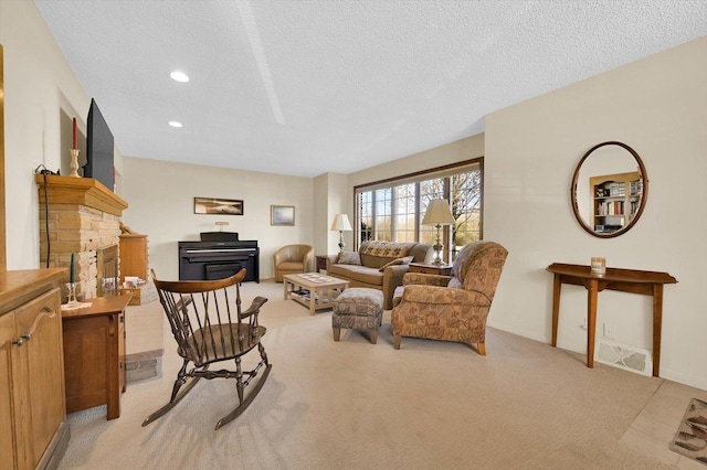 living area with a textured ceiling, light colored carpet, visible vents, recessed lighting, and a fireplace