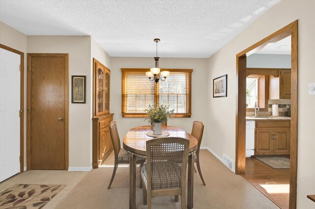 dining room with a textured ceiling, visible vents, a notable chandelier, and light carpet