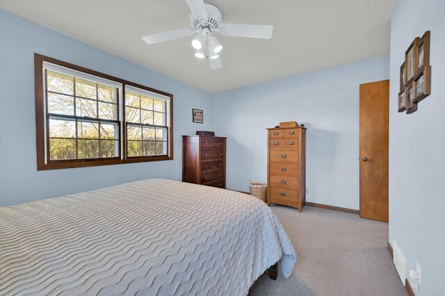 bedroom with ceiling fan, light colored carpet, and baseboards
