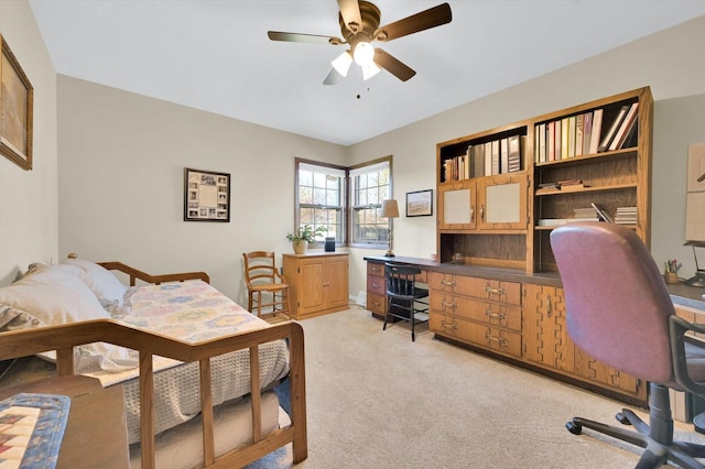 bedroom with a ceiling fan, built in study area, and light carpet