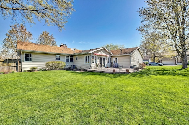 rear view of house with fence, cooling unit, a chimney, and a lawn