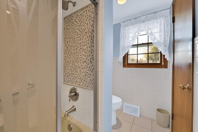 full bath featuring tile walls, tile patterned floors, toilet, combined bath / shower with glass door, and visible vents