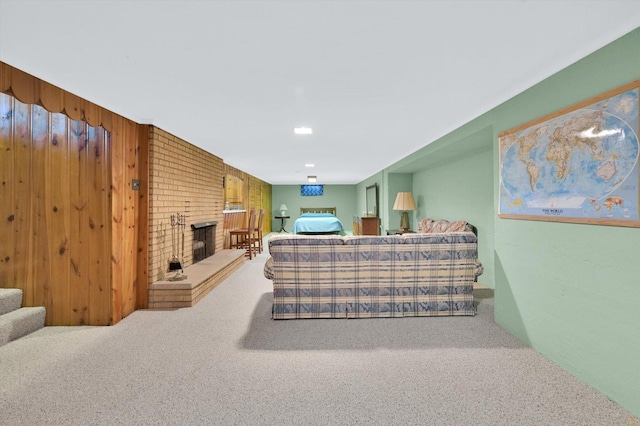 carpeted living room with wood walls, stairway, and a brick fireplace
