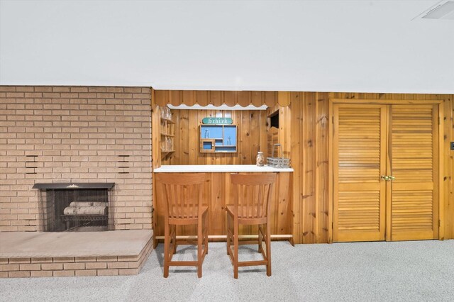 bar with a brick fireplace, a dry bar, wood walls, and carpet floors