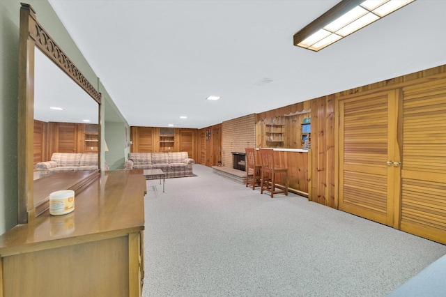 living area featuring a fireplace, wood walls, recessed lighting, and carpet flooring