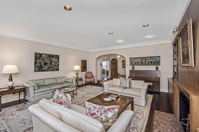 living area featuring recessed lighting, wood finished floors, ornamental molding, arched walkways, and baseboards
