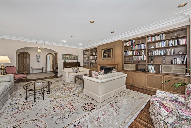 living area with wood finished floors, arched walkways, recessed lighting, and crown molding