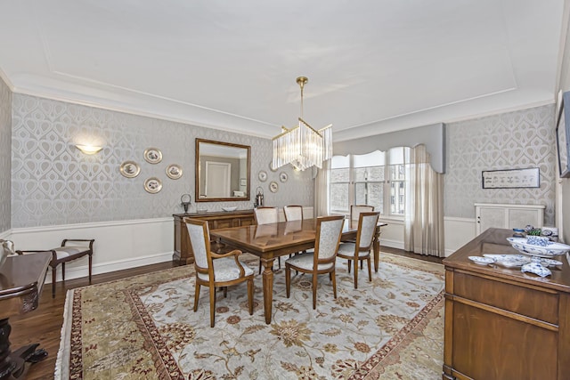 dining space with wallpapered walls, crown molding, wainscoting, and an inviting chandelier