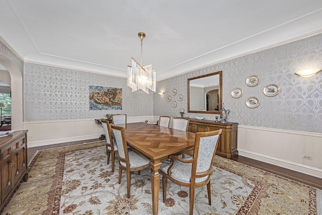 dining area with wainscoting, wallpapered walls, a notable chandelier, and crown molding