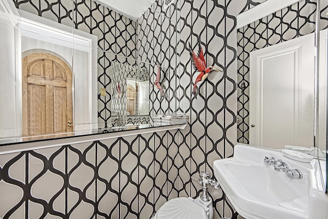 bathroom featuring a sink and wallpapered walls