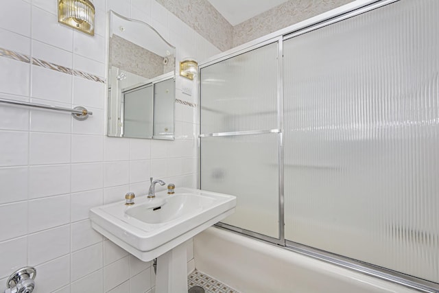 full bath featuring tasteful backsplash, tile walls, and bath / shower combo with glass door