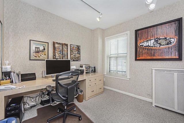 carpeted office space featuring radiator heating unit, wallpapered walls, track lighting, and baseboards