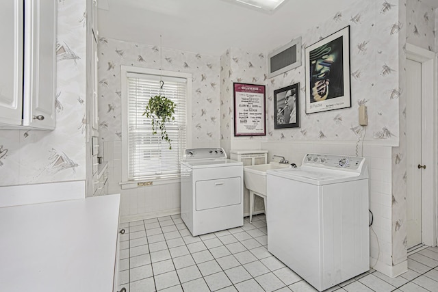 laundry area featuring washer and clothes dryer, wallpapered walls, a sink, light tile patterned flooring, and cabinet space