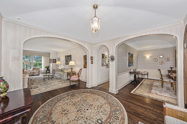 foyer entrance with baseboards, wood finished floors, arched walkways, and ornamental molding