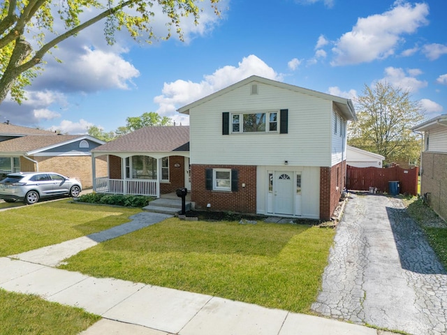 tri-level home featuring brick siding, covered porch, asphalt driveway, and central air condition unit