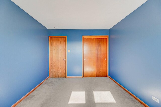 unfurnished bedroom with carpet floors, baseboards, and a closet