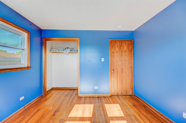 unfurnished bedroom with baseboards, a closet, and wood finished floors