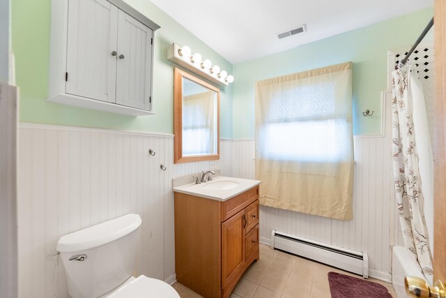 full bathroom with baseboard heating, a wainscoted wall, toilet, vanity, and tile patterned floors