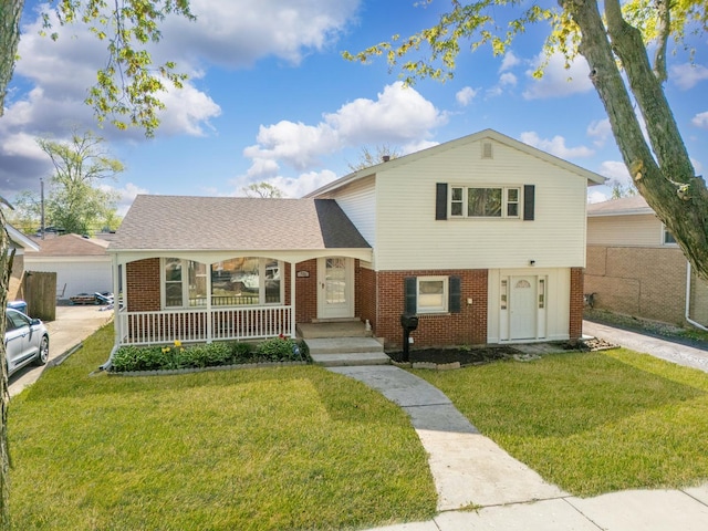 tri-level home featuring brick siding, a front yard, and covered porch