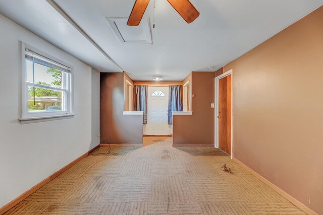 empty room featuring light carpet, attic access, a ceiling fan, and baseboards