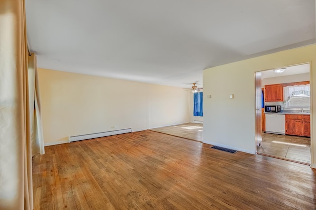 empty room featuring a baseboard radiator, light wood-style floors, ceiling fan, and baseboards
