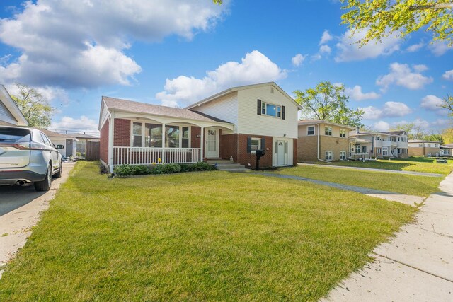 split level home with brick siding, a front yard, and a porch