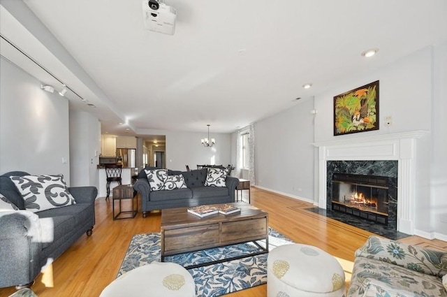living room featuring a chandelier, a high end fireplace, and light wood-style flooring