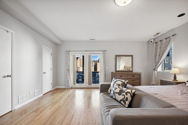 bedroom featuring baseboards, wood finished floors, visible vents, and access to exterior