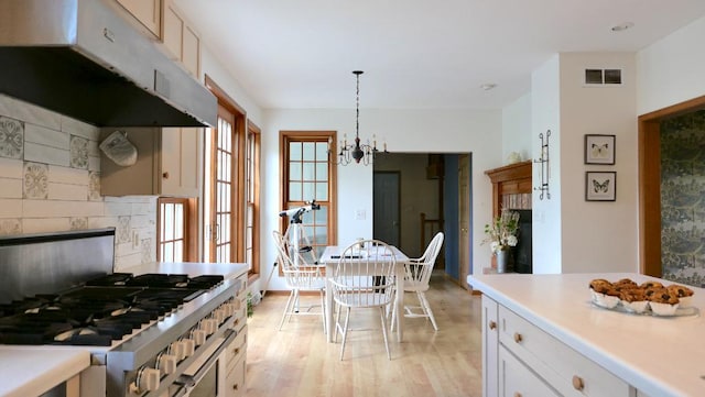 2346 W Longhollow Rd, Elizabeth, IL 61028 - kitchen with under cabinet range hood, range with gas cooktop, light wood-type flooring, white cabinetry, and a chandelier