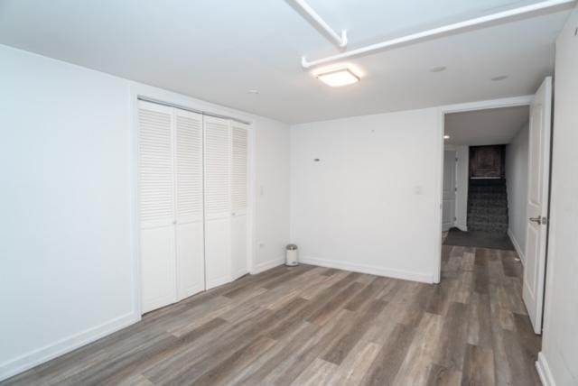 unfurnished bedroom featuring baseboards, wood finished floors, and a closet