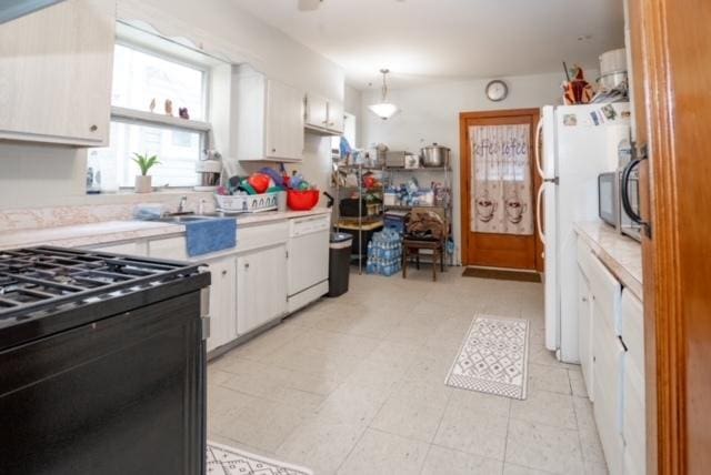 kitchen with light countertops, a sink, white cabinets, and white appliances
