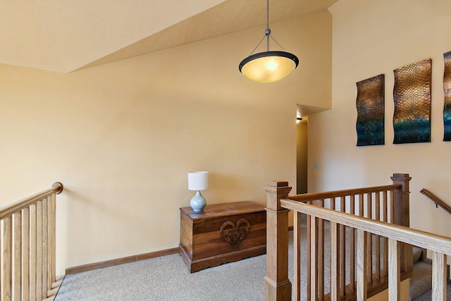 corridor featuring an upstairs landing, lofted ceiling, carpet, and baseboards