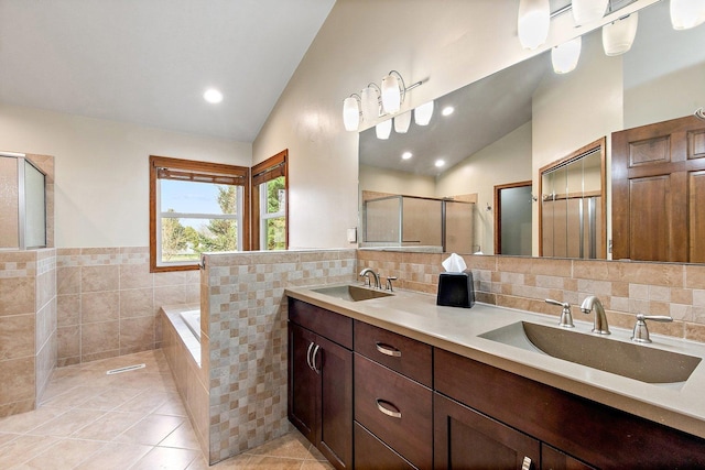 full bath with tile walls, tile patterned floors, a shower stall, and a sink