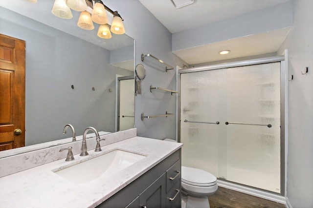 bathroom with toilet, wood finished floors, a shower stall, and vanity