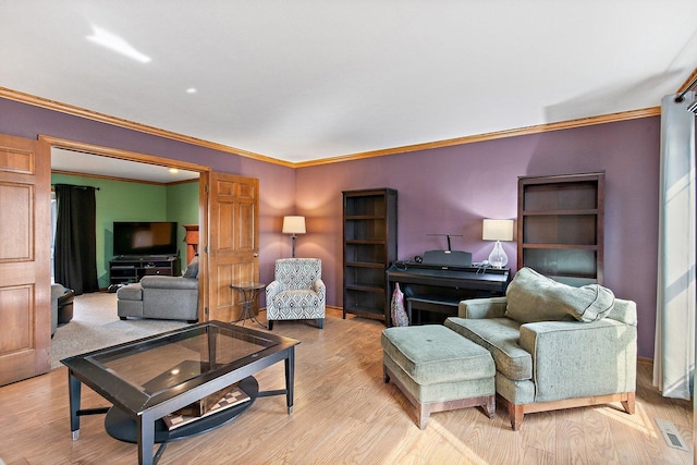 living room with crown molding, visible vents, and light wood-type flooring