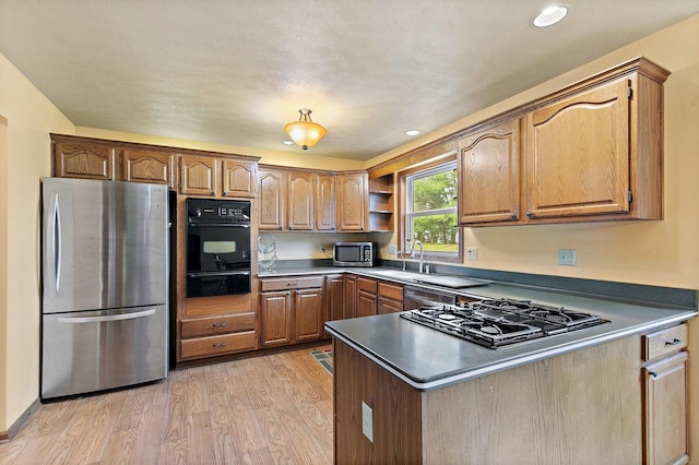 kitchen featuring light wood finished floors, open shelves, a warming drawer, black appliances, and a peninsula