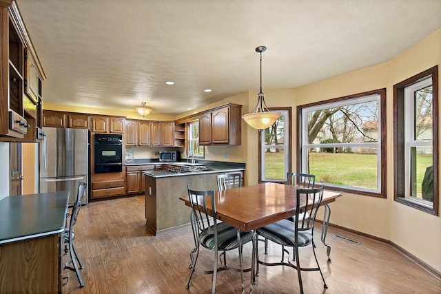 kitchen with wood finished floors, open shelves, appliances with stainless steel finishes, a warming drawer, and baseboards