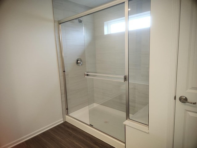 bathroom with wood finished floors, a stall shower, and baseboards