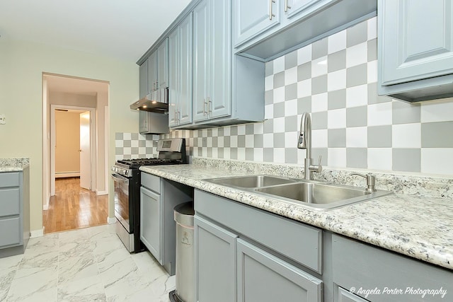 kitchen featuring a sink, light countertops, stainless steel range with gas cooktop, backsplash, and under cabinet range hood