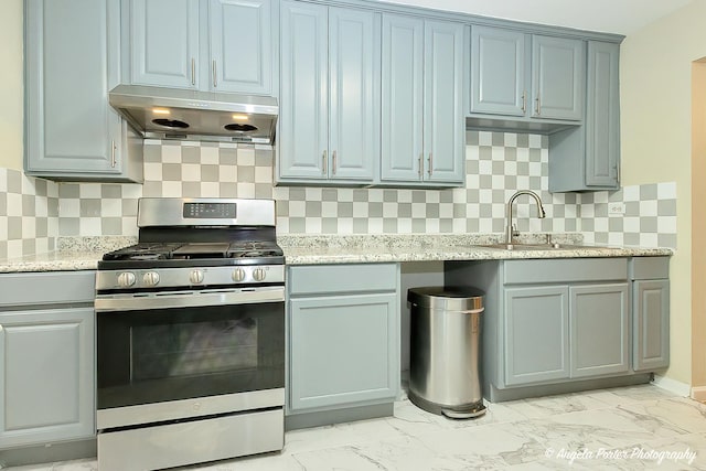 kitchen featuring stainless steel range with gas cooktop, a sink, marble finish floor, and under cabinet range hood