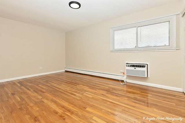 spare room with an AC wall unit, light wood-style flooring, baseboards, and baseboard heating