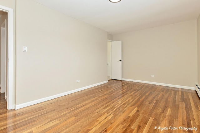 spare room featuring baseboards and light wood finished floors