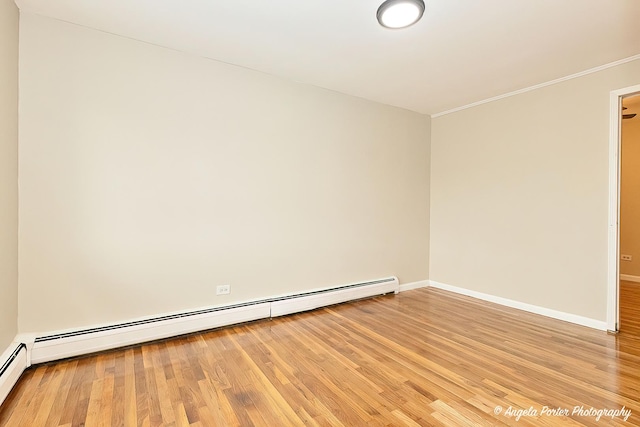 spare room with baseboards, baseboard heating, and light wood-type flooring