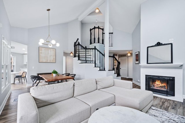 living room featuring a chandelier, stairs, high vaulted ceiling, and dark wood-style flooring