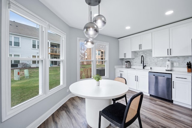kitchen with dark wood-style floors, a sink, backsplash, dishwasher, and light countertops