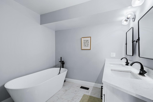 full bath with marble finish floor, baseboards, a freestanding bath, and a sink