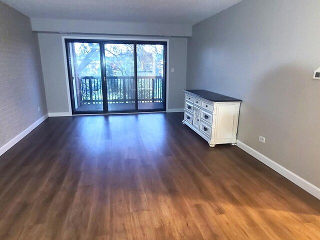 unfurnished room featuring baseboards and dark wood-style flooring
