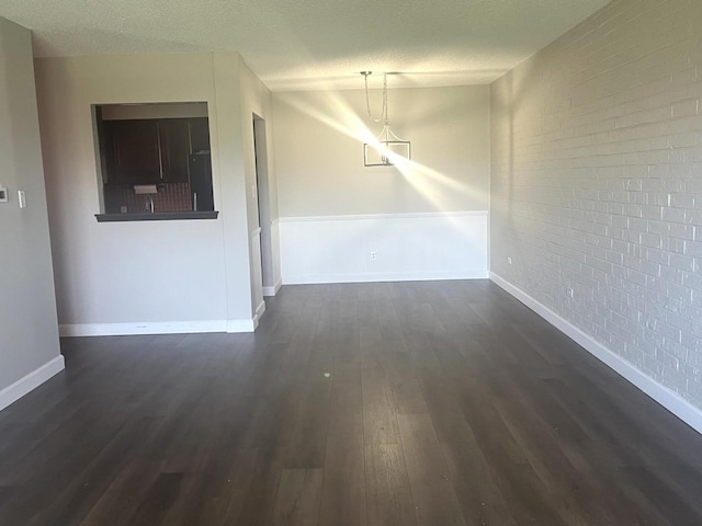 unfurnished dining area with baseboards, dark wood-style flooring, and brick wall